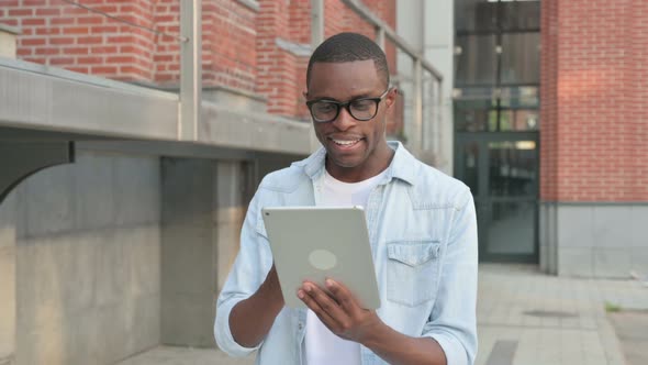 African Man Doing Video Call on Tablet While Walking in Street