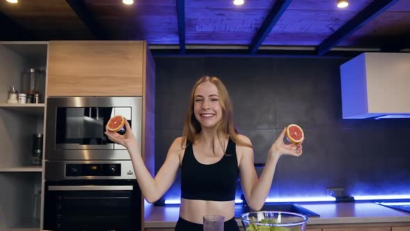 Young Woman Holding Two Halves of Grapefruit in Her Hands and Making with them Glasses on Her Eyes