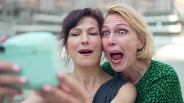 Relaxed Women Having Fun Grimacing Taking Selfie on Camera Standing Outdoors