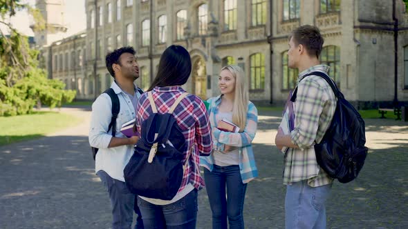 Group of Cheerful Students Actively Communicating Standing in University Yard