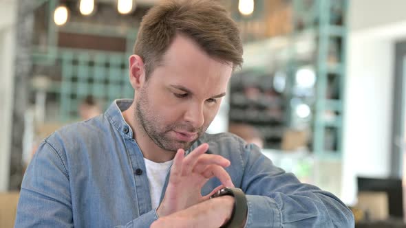 Portrait of Curious Casual Man Using Smart Watch