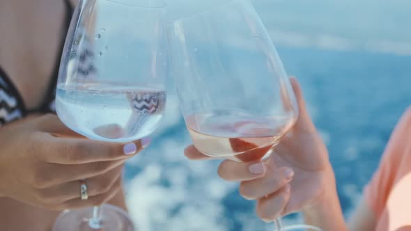 Friends raising wine glasses outdoors.  Two woman Toasting  and drinking champagne.  Slow motion.