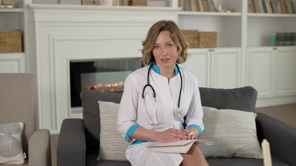 Happy Female Doctor Waving Hello to Patient During Home Care Visit