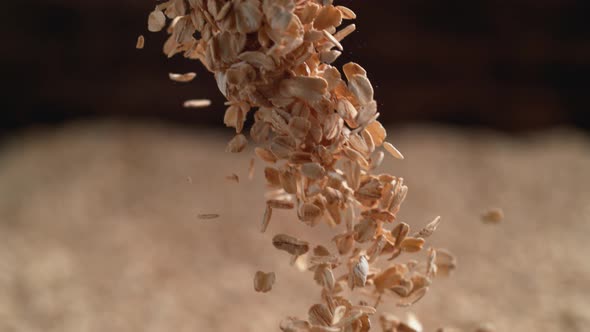 Camera follows throwing oats over a pile of oats. Slow Motion.