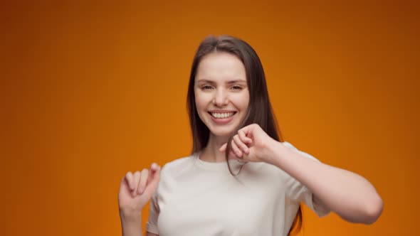 Happy Young Woman Dancing with Joy Against Yellow Background