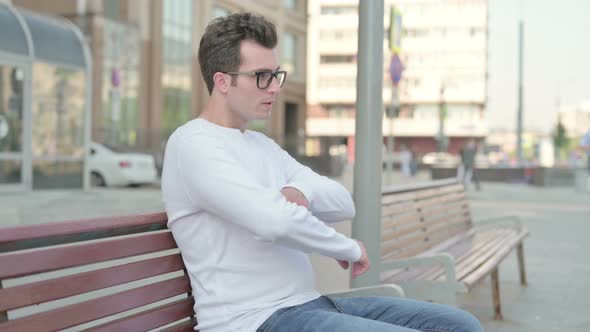 Young Man Looking at Camera While Sitting on Bench