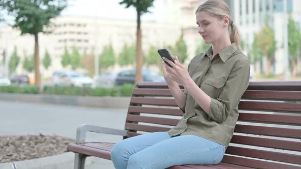 Woman Using Smartphone while Sitting Outdoor on Bench