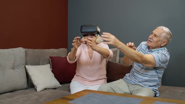 Senior Woman Playing Game in Virtual Reality Headset Glasses, Man Laughing with Her Action at Home
