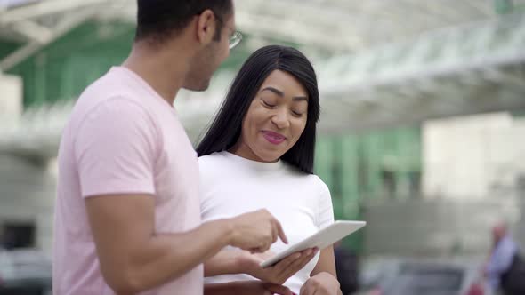 Joyful Friends Standing on Street and Using Tablet