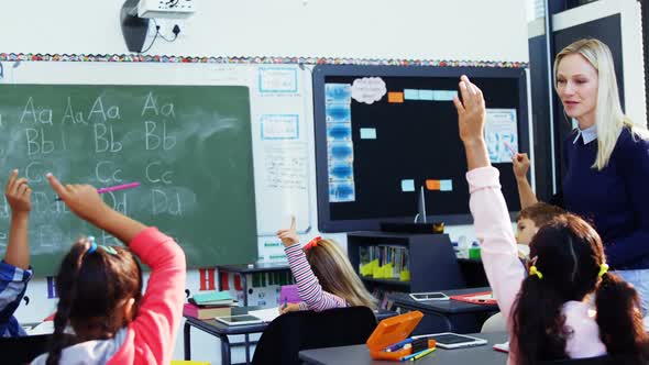 Teacher asking questions to her students in classroom