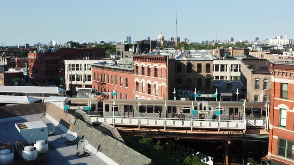 A slow aerial reveal of the Chicago skyline beyond train station as a rail trail departs.