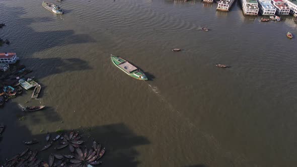 Aerial: dockyard at Buriganga river bank with city landscape in Dhaka, Bangladesh - drone tilt up sh