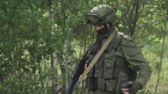 Soldier in Camouflage Reloads the Kalashnikov Assault Rifle Military Action in Forest