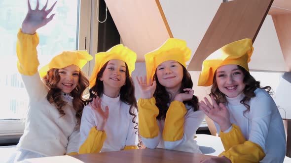 Children in yellow hats help to cook pizza in the kitchen