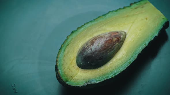 Half of an Avocado with a Stone Rotates in a Circle on a Black Background