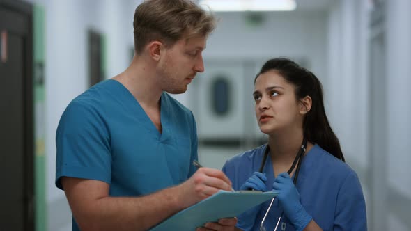 Surgeon Discussing Patient Diagnosis with Nurse Standing Clinic Corridor Closeup