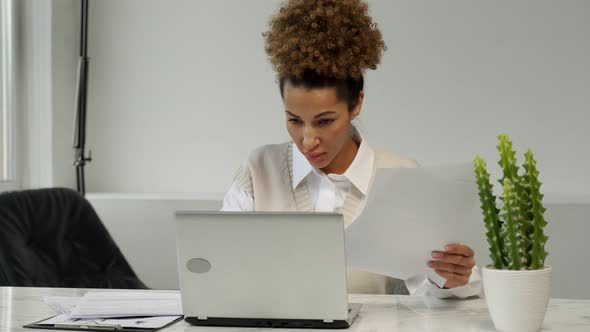 Angry AfricanAmerican Businesswoman Who Has Problems in the Office Holds Office Papers