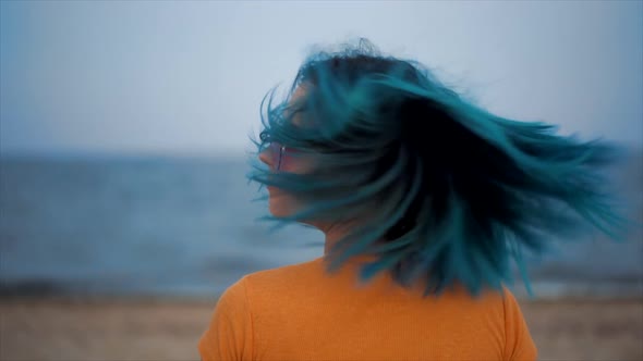 Unusual Woman Shakes Her Blue Dyed Hair on Sea Beach Background. Portrait of Hipster Girl with