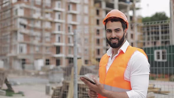 Portrait of Construction Worker on Building Site with Tablet Looking at the Camera. Professions