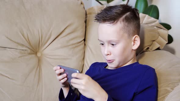 Cute kid playing games on smartphone. Little boy playing tablet game. Peaceful pastime.