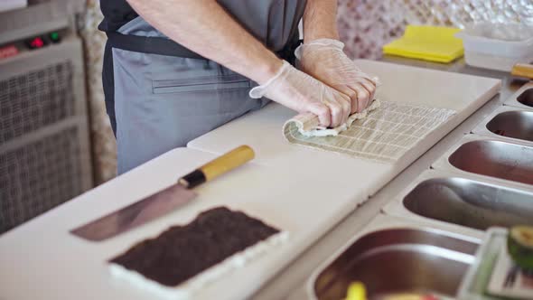 Male Hands in Gloves Cooking Sushi Rolls in a Restaurant Kitchen Close Up