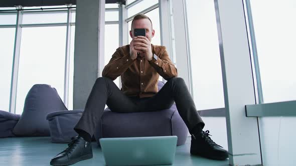 Handsome businessman writing notes from smartphone at modern office