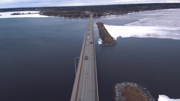 4K Aerial Shot of Cars Driving Over Icy Water on a Huge Highway Bridge Surrounded by a Large Frozen