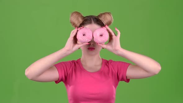 Girl Holds Donuts in Her Hands and Closes Her Eyes. Green Screen