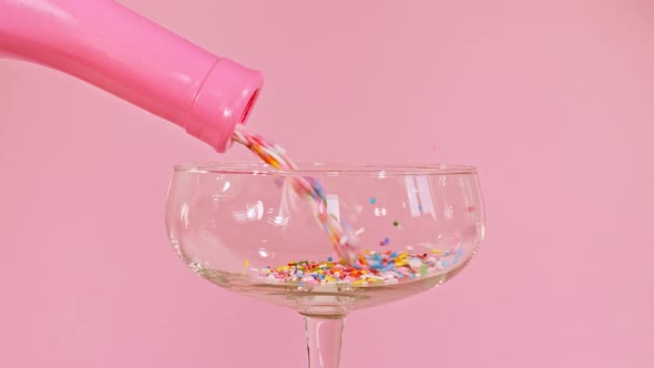 Colorful Candy Confectionery Run Poured Into a Wineglass Glass on Pink Background