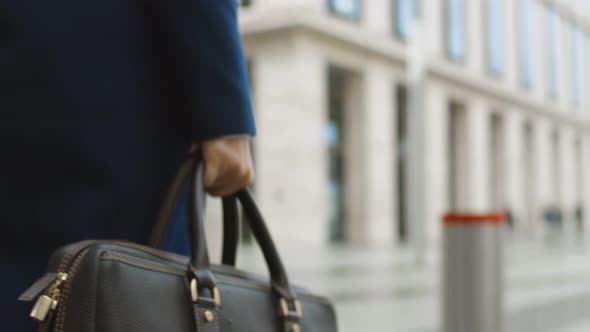 Back View of Confident Businesswoman Wearing Coat Carrying Briefcase Walking Outside