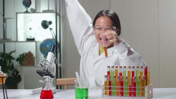 Excited Young Asian Scientist Girl Mixes Chemicals In Test Tube. Child Learn With Interest