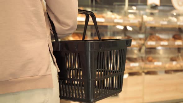 Young Woman with Shopping Basket in Supermarket Rear View