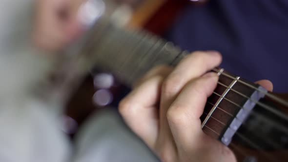 the White Fingers of the Guitarist Clamp the Strings on the Rosewood Neck of the Guitar