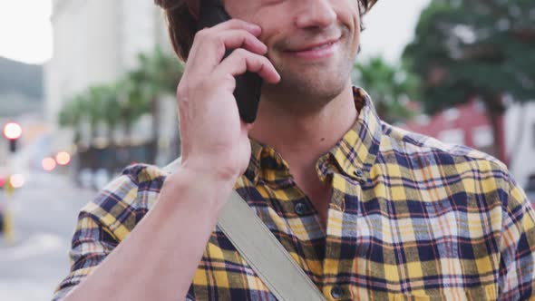 Caucasian male talking and using his phone in a street