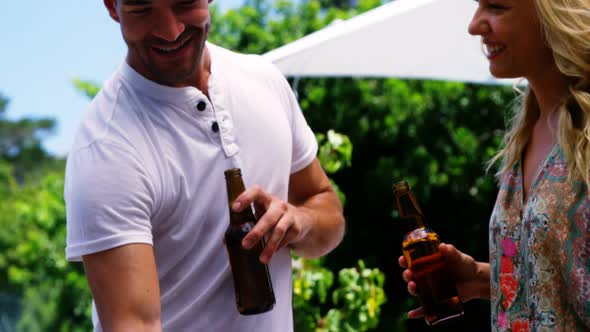 Group of friends having a bottle of beer while preparing barbeque