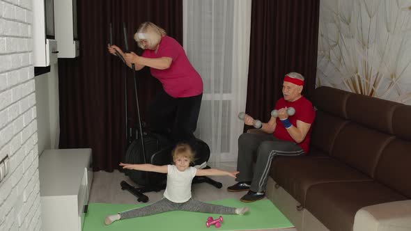Senior Couple with Granddaughter Using Orbitrek Doing Weight Lifting Dumbbells Exercises at Home