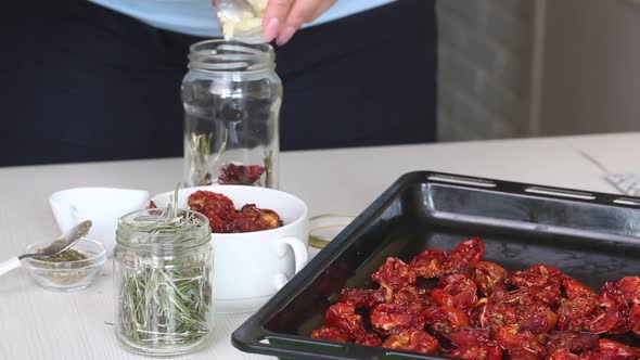 A Woman Mixes Spices And Sun Dried Tomatoes In A Jar. Cooking Sun Dried Tomatoes In Olive Oil.