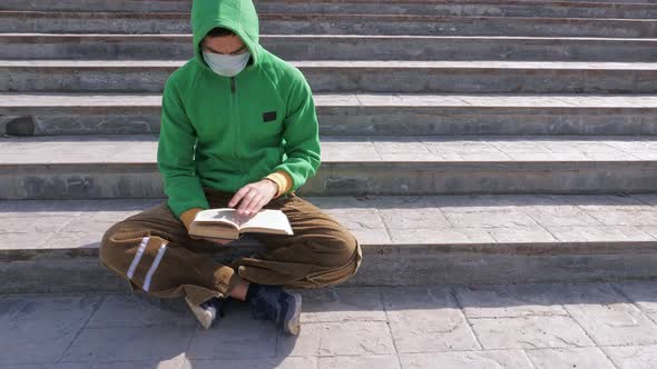 Young Man Reading Book on Street During Epidemic