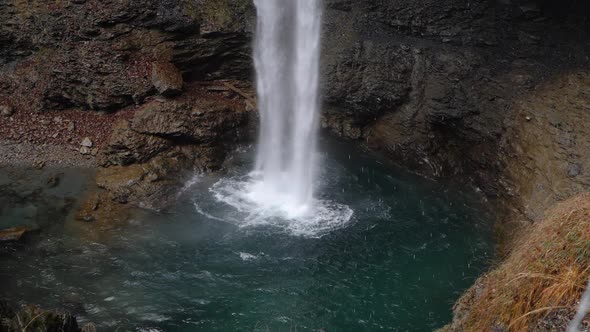 Slow motion shot of a waterfall on a rocky reddish cliff and clear water