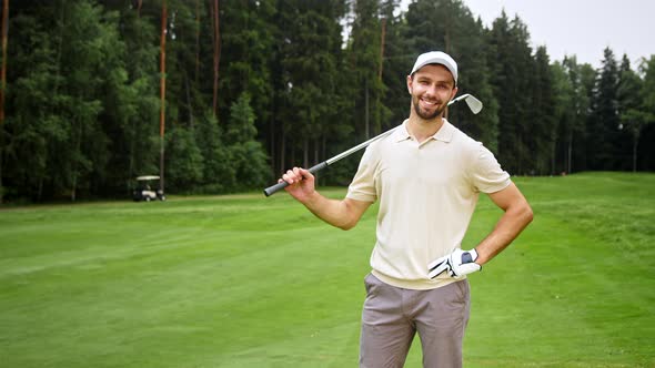 Young man with golf club looking at camera