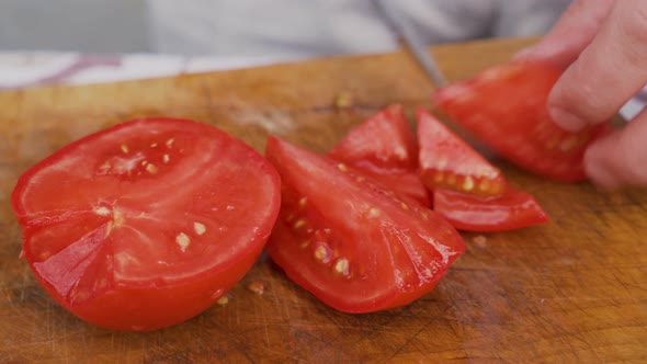 Close View of Male Hands Cutting Fresh Red Tomato on Board to Prepare Salad