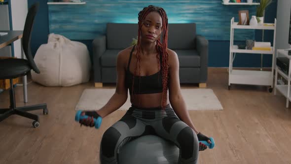 Fit Woman with Dark Skin Doing Exercises with Fitness Dumbbells Sitting on Swiss Ball