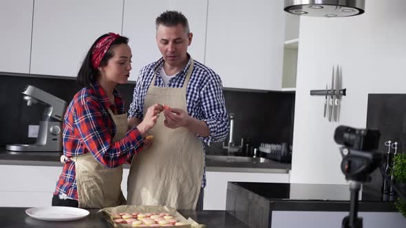 Adult Couple at Kitchen Baking at Home Talking on Camera and Tasting Cookies