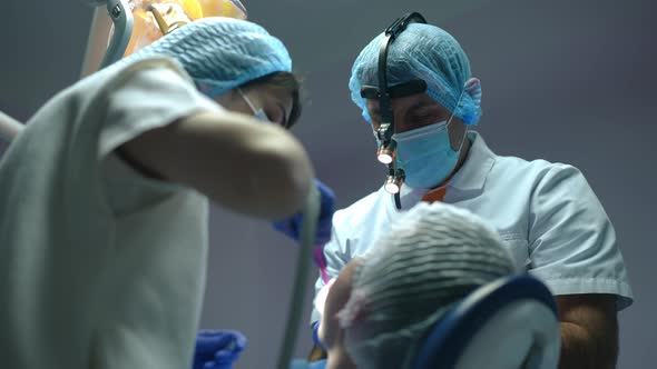 Professional Focused Dentist Cleaning Tooth Hole in Slow Motion As Assistant Removing Saliva From