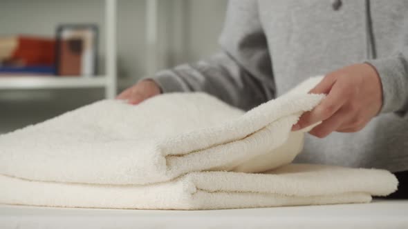 Young Woman Putting Washed Dry Clean Towels on Iron Board Preparing for Ironing