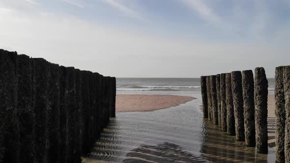 Row Of Old Wooden Piles On Seashore With Splashing Waves In Brouwersdam, Netherlands. - Dolly Shot