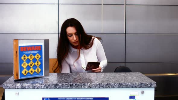 Female airport staff checking passport at check-in desk