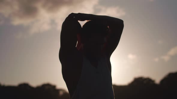 Man In Park Stretching Before Excercise Whilst Weing Silouetted By The Sun In Slow Motion