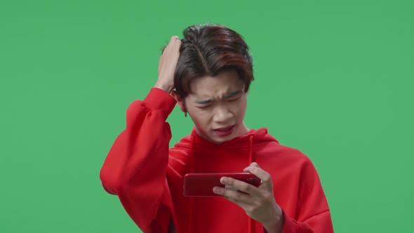 Upset Asian Transgender Male Losing Mobile Phone Game On The Green Screen Background