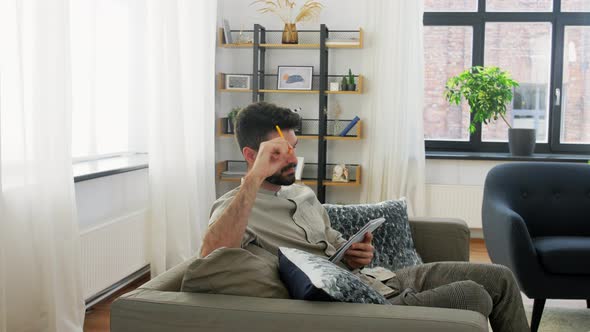 Man Writing To Notebook and Thinking at Home